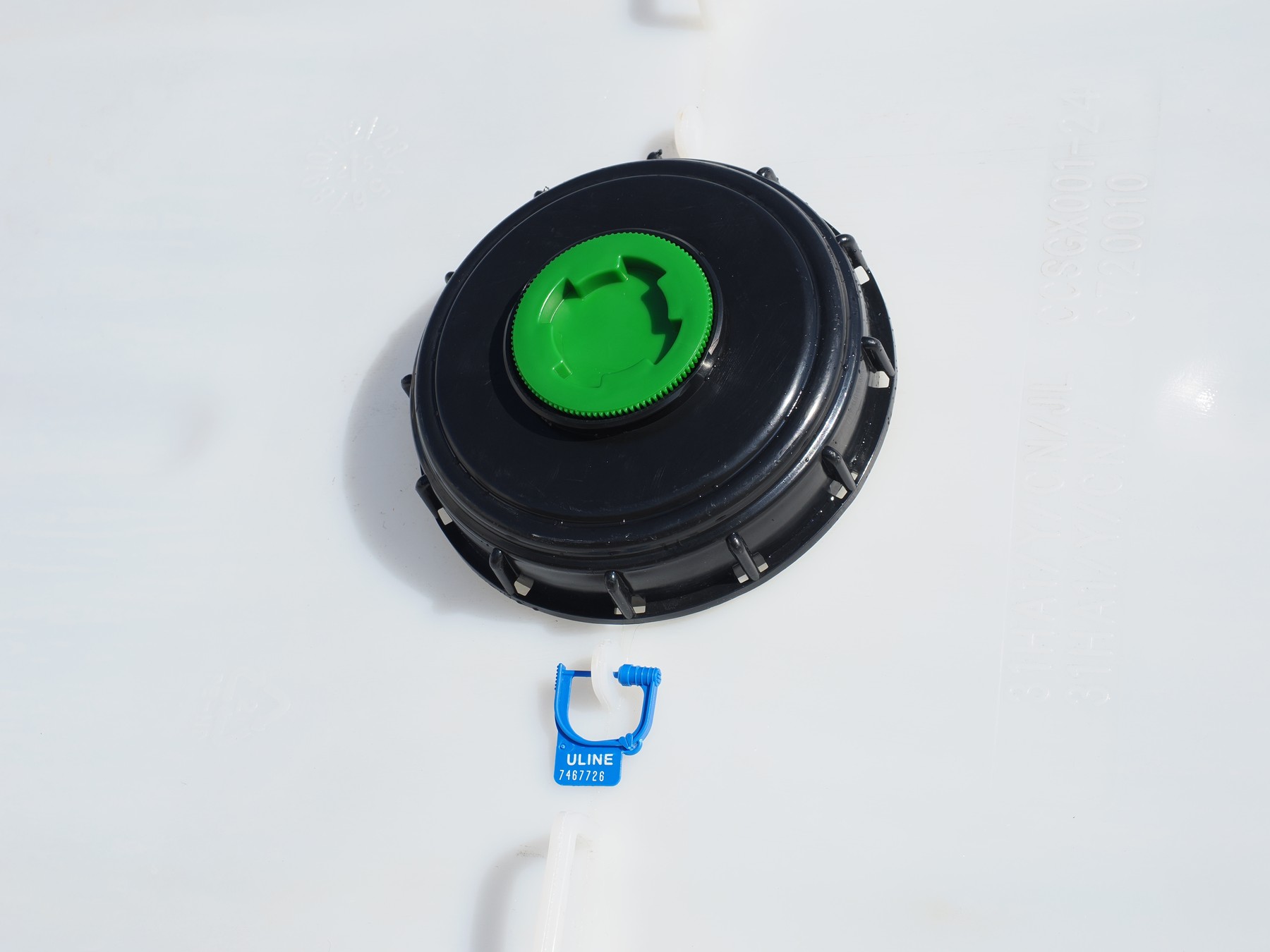 IBC top lid with green tamper-evident bung and an individual identification tag